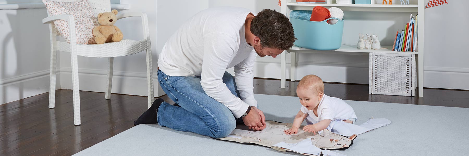 Dad changes baby diaper with The Wriggler portable changing pad