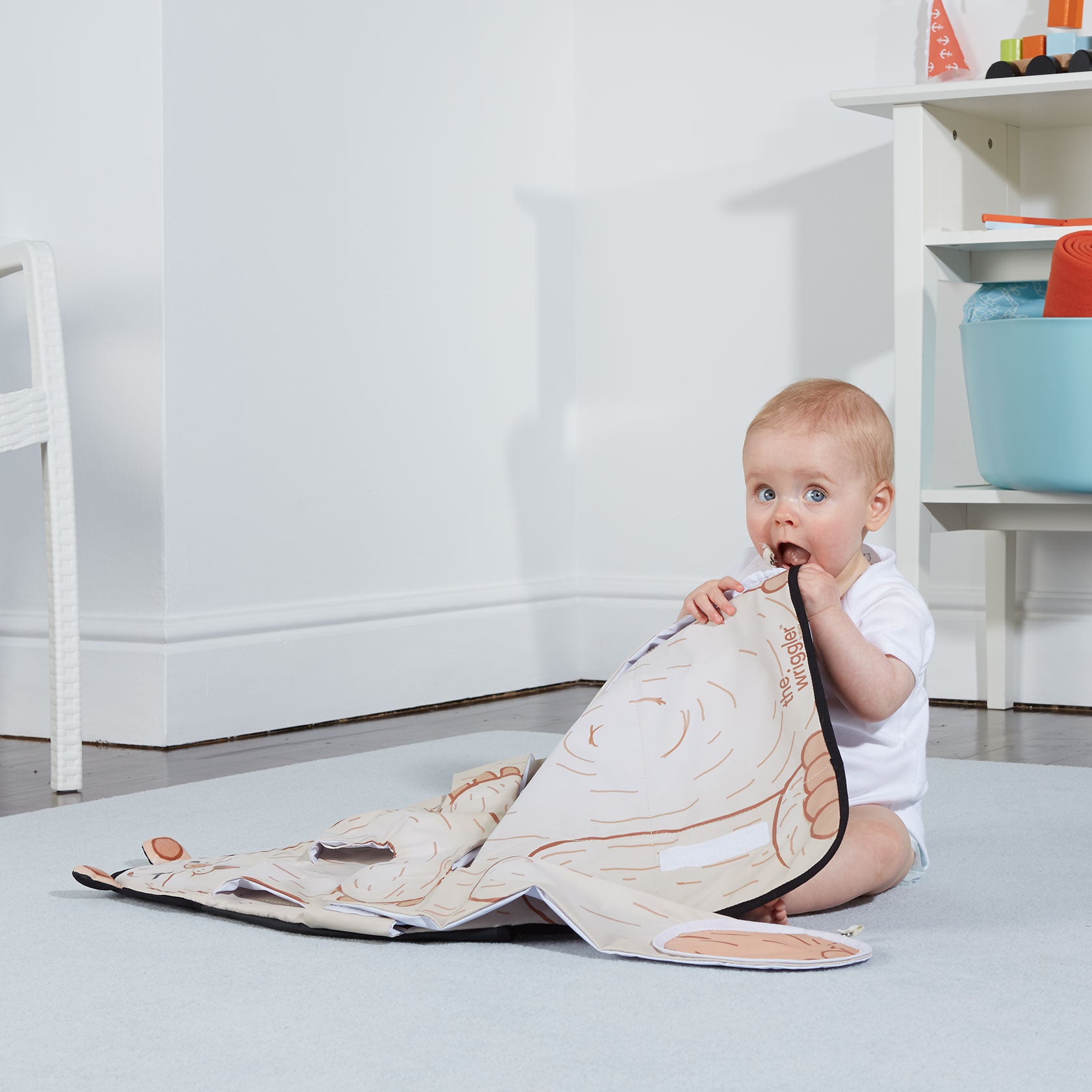 Baby placing The Wriggler changing pad in her mouth to show that the materials are BPA and phthalate free and rigorously safety tested to meet international safety standards
